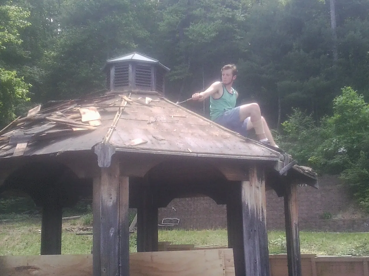 Tearing the old roof off a wooden gazebo before new shakes in Emerson