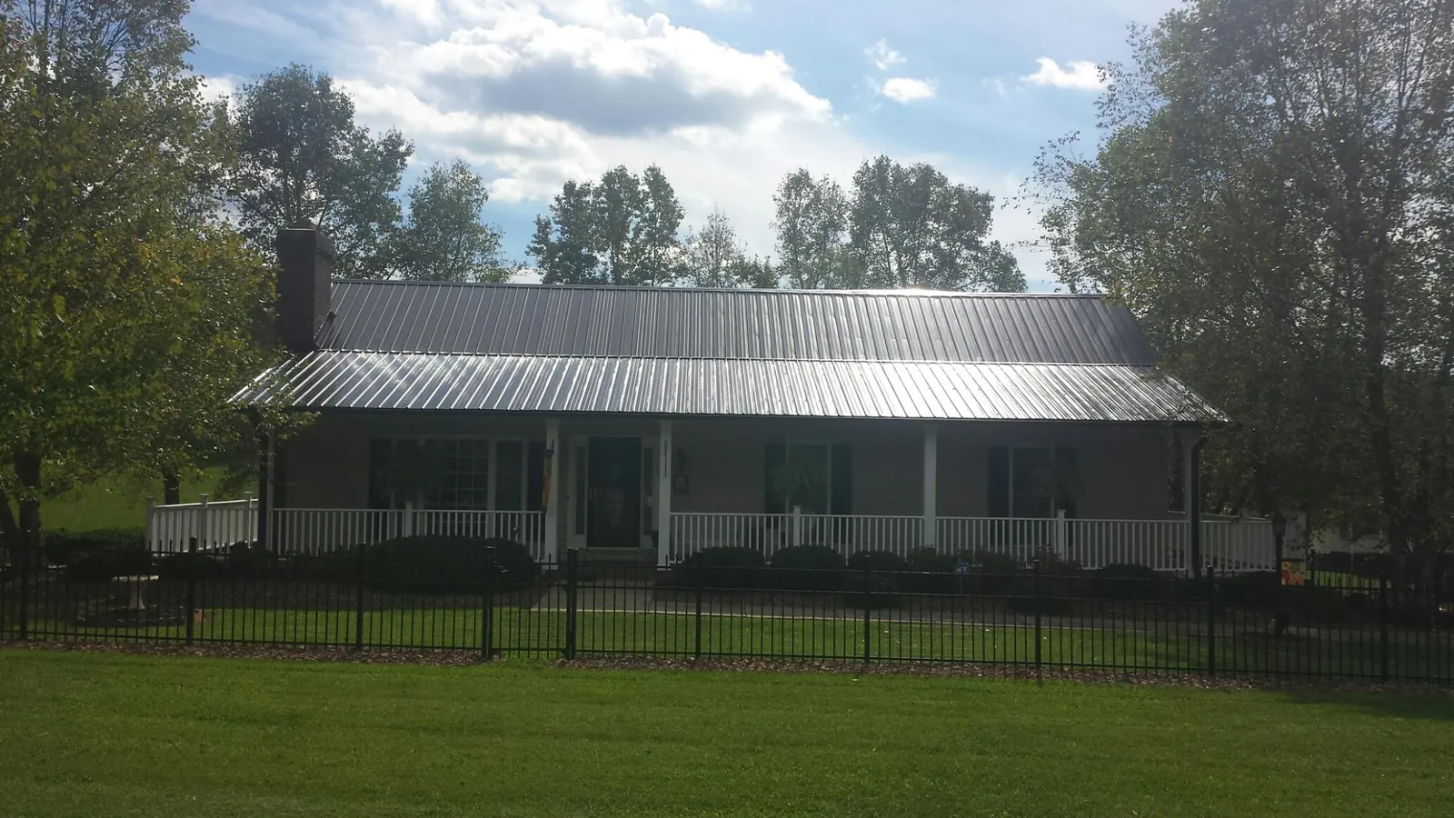 Gray metal roof on a brick ranch with a full width front porch — Gutter Guard Installation work by our crew in Emerson